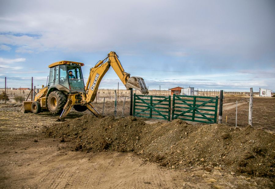 Backhoe digging out an old culvert at a rural field gate